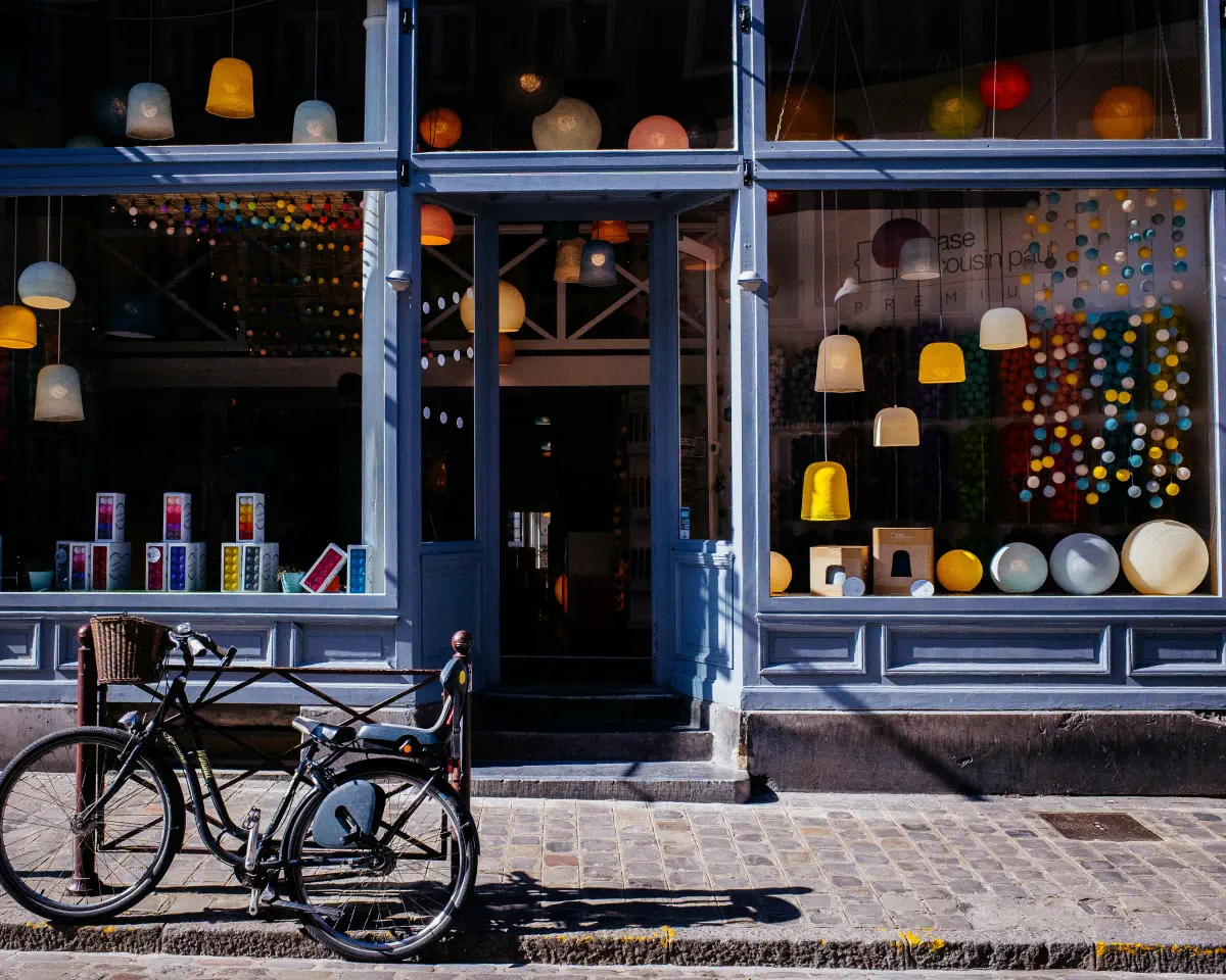 A bright European high-street storefront with a bicycle parked outside, illustrative of one of your own stores kept back from the model for the Validation Sprint.